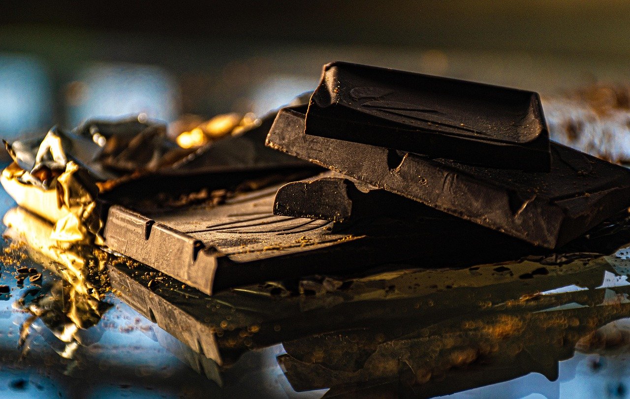 Luxury dark chocolate pieces with golden foil on a reflective surface