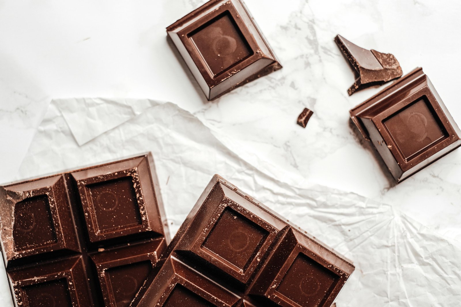Close-up of broken dark chocolate bar on white background