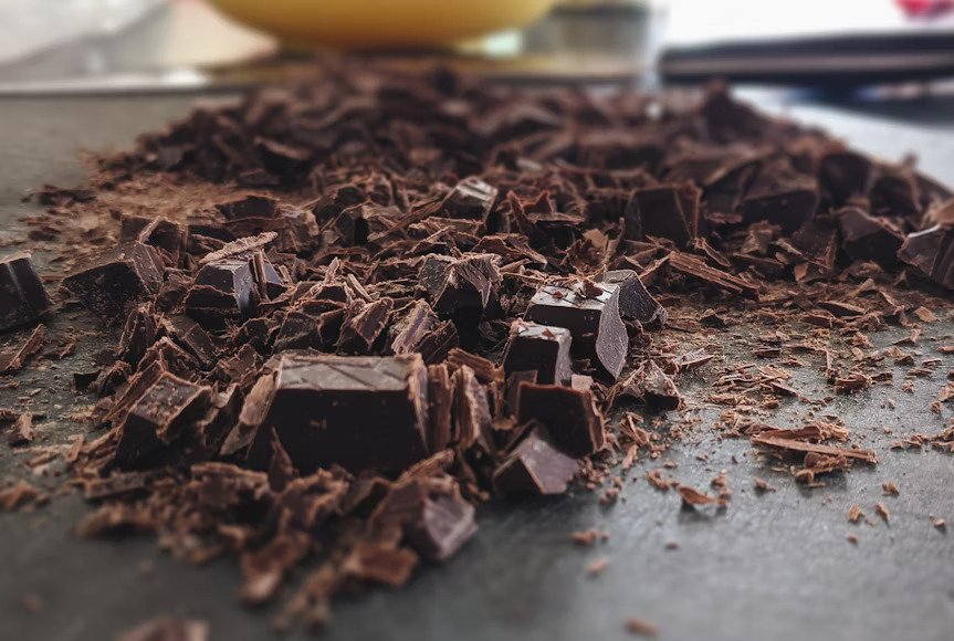 Chopped dark chocolate chunks and shavings on a dark surface, ready for use in a luxury recipe.
