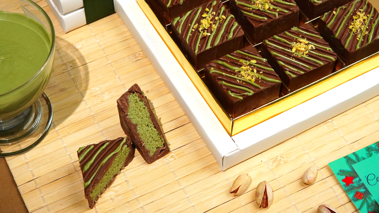 Luxury Pistachio Kunafa Mini Bars coated in rich chocolate with pistachio drizzle on a wooden serving board.