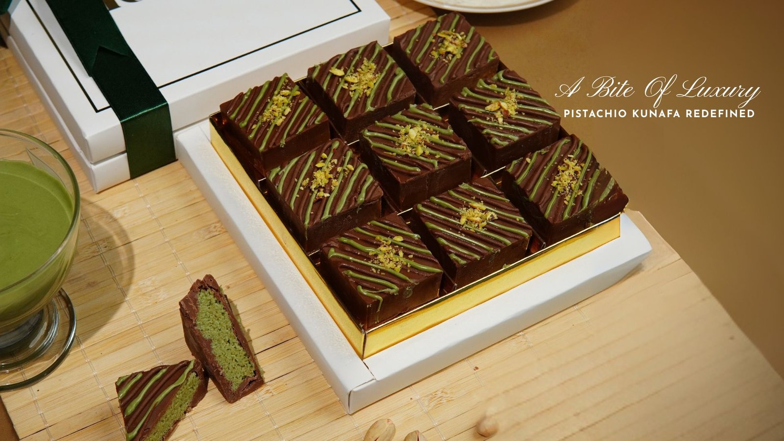 Box of luxury pistachio kunafa chocolates with green drizzle and nut topping placed on a wooden surface.
