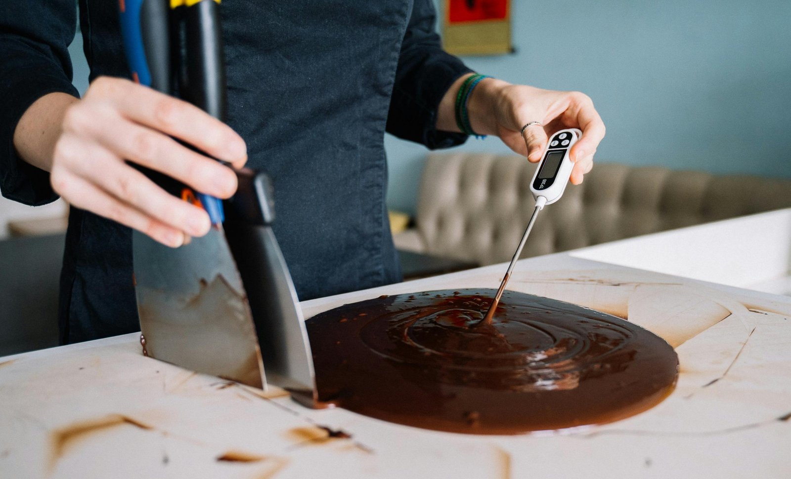 A person checking the temperature of melted chocolate with a digital thermometer.