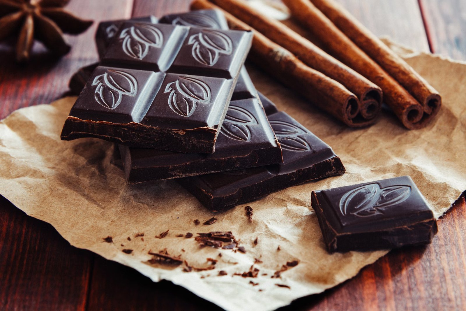 Dark chocolate bars with different cocoa percentages arranged on a rustic background.